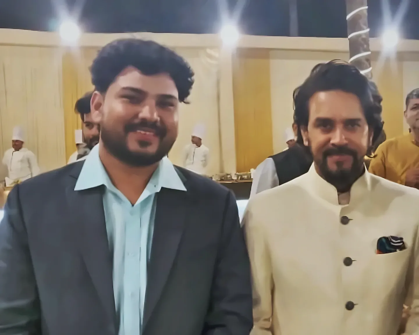 Prem Mishra with a guest at an evening event, with catering staff and lights behind them
