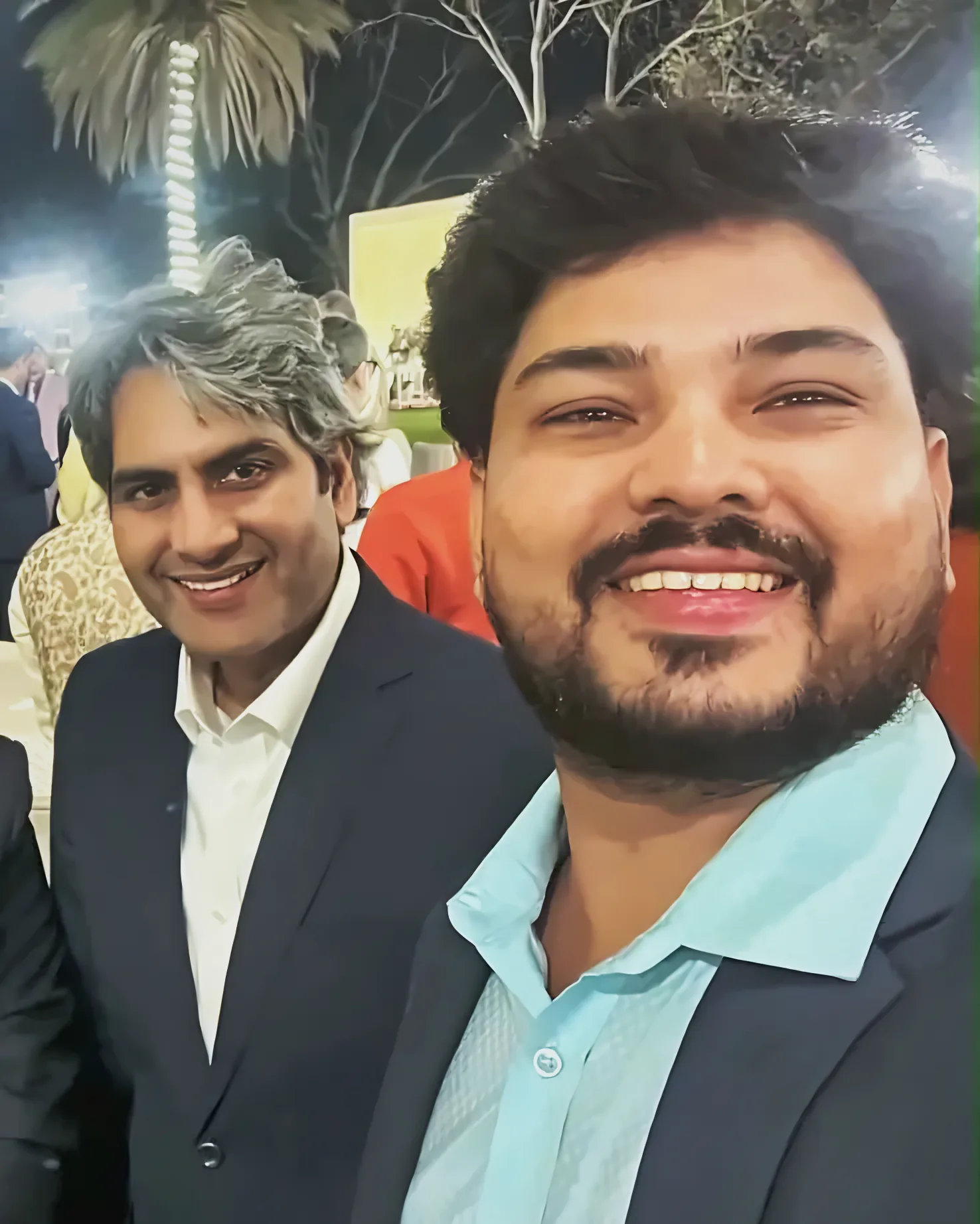 Prem Mishra taking a selfie with a guest at an outdoor evening reception