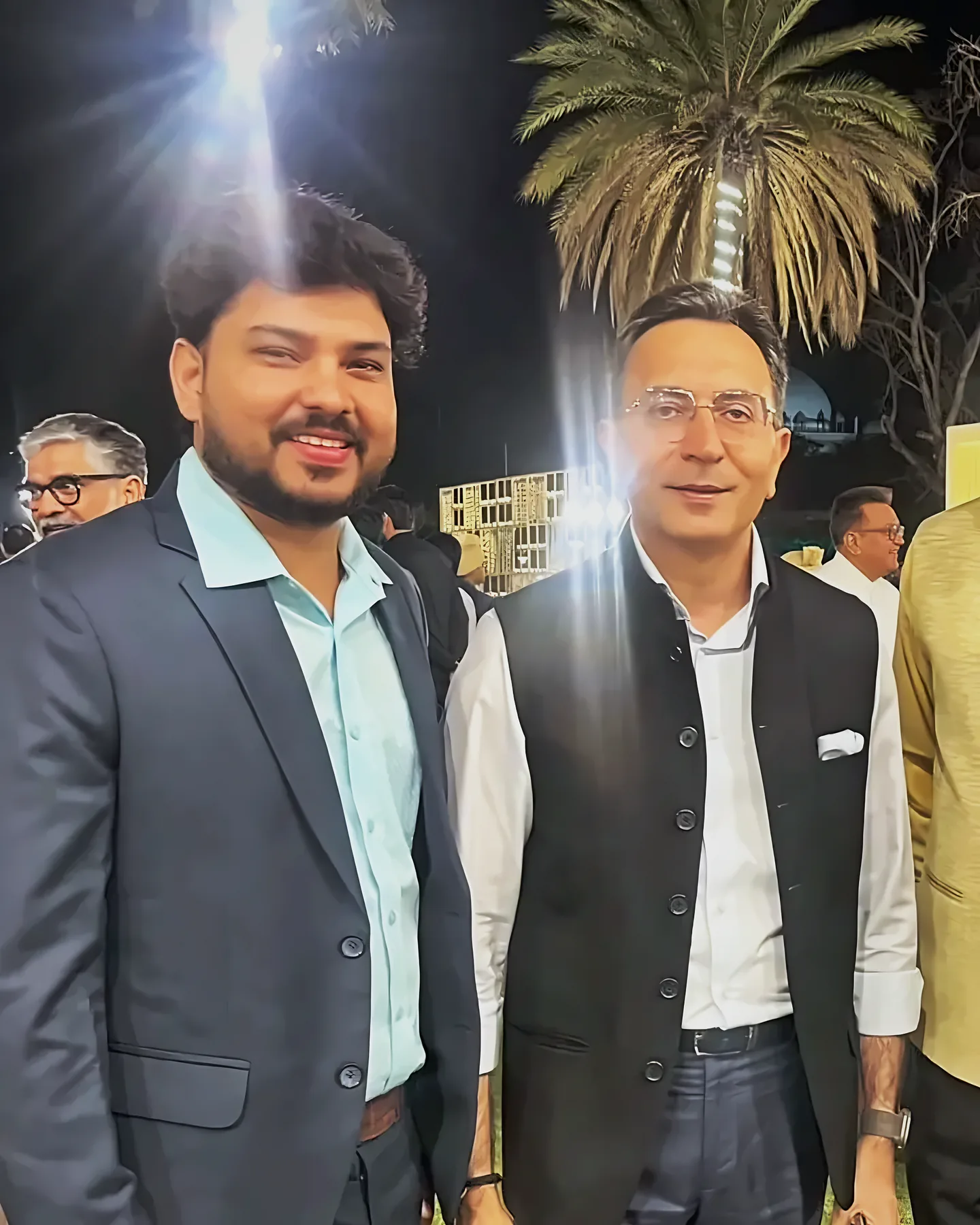 Prem Mishra standing with a guest on the lawn at a night-time reception