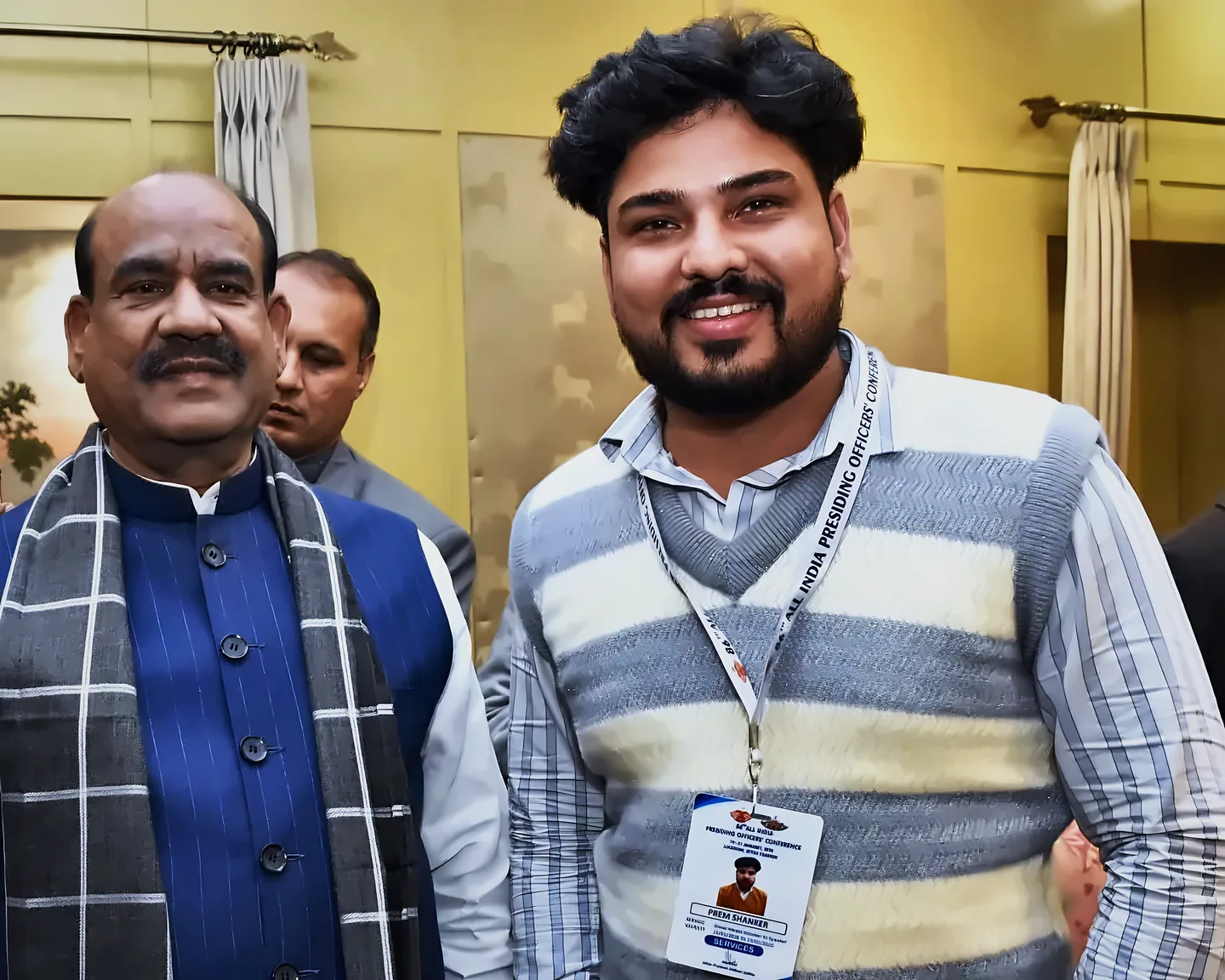 Prem Mishra, wearing a conference delegate badge, with a guest at an indoor event