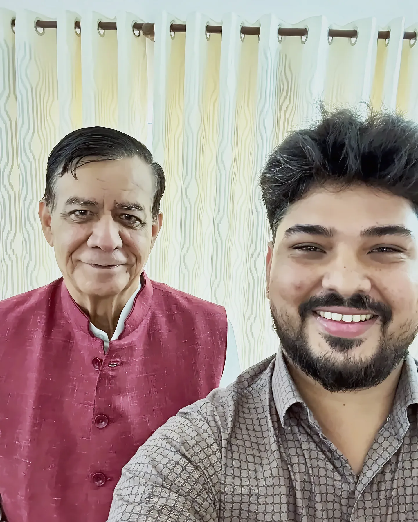 Prem Mishra taking a selfie with an older guest in front of a cream curtain